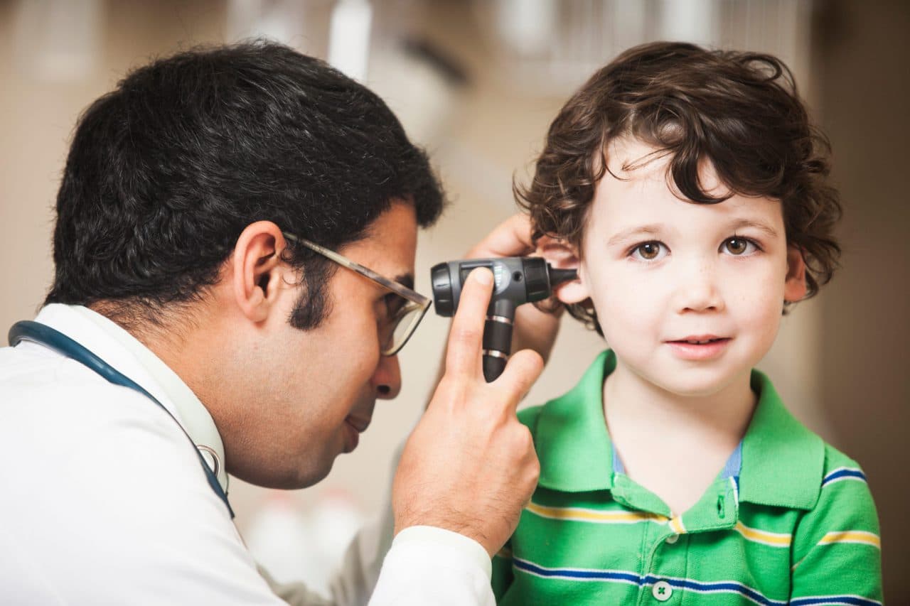 A child getting examined by an audiologist using an otoscope