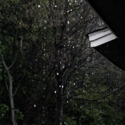 Rain falling from the sky and dripping off a house gutter.