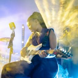 Female musician playing guitar on stage.