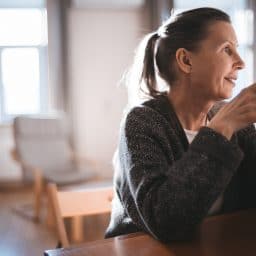 Woman drinking coffee at her kitchen table.