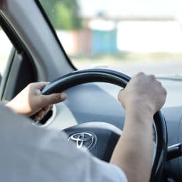 Man driving with hands on steering wheel.