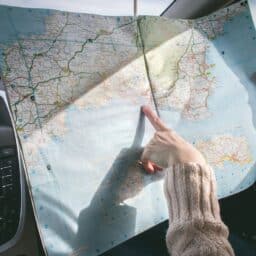 Passenger in a car points at a map on a roadtrip.