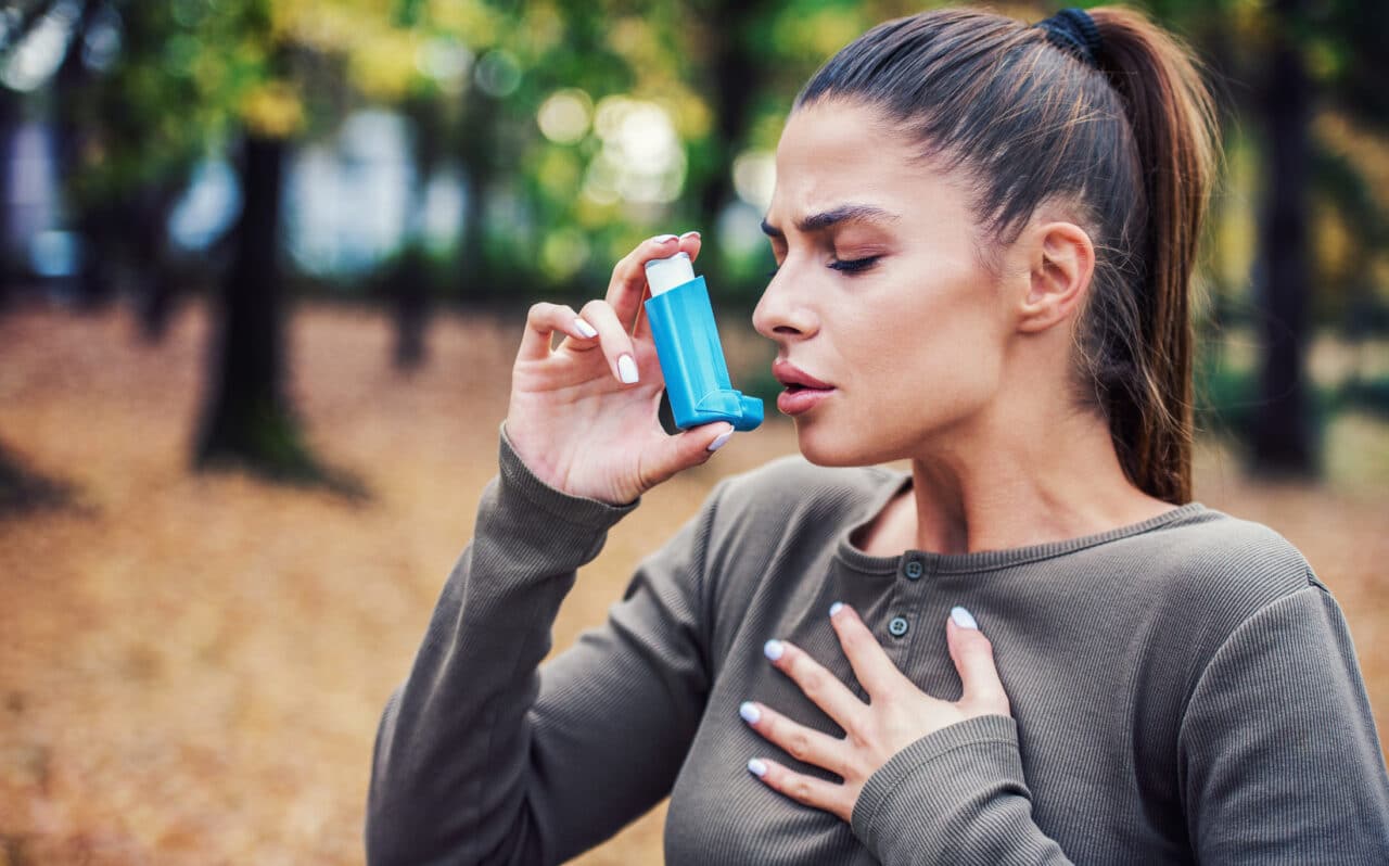 Young woman using an inhaler to treat asthma symptoms.