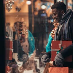 A couple looking through a shop window holding gifts