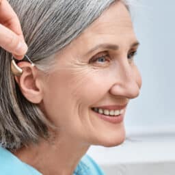 Hearing aid is placed behind woman's ear