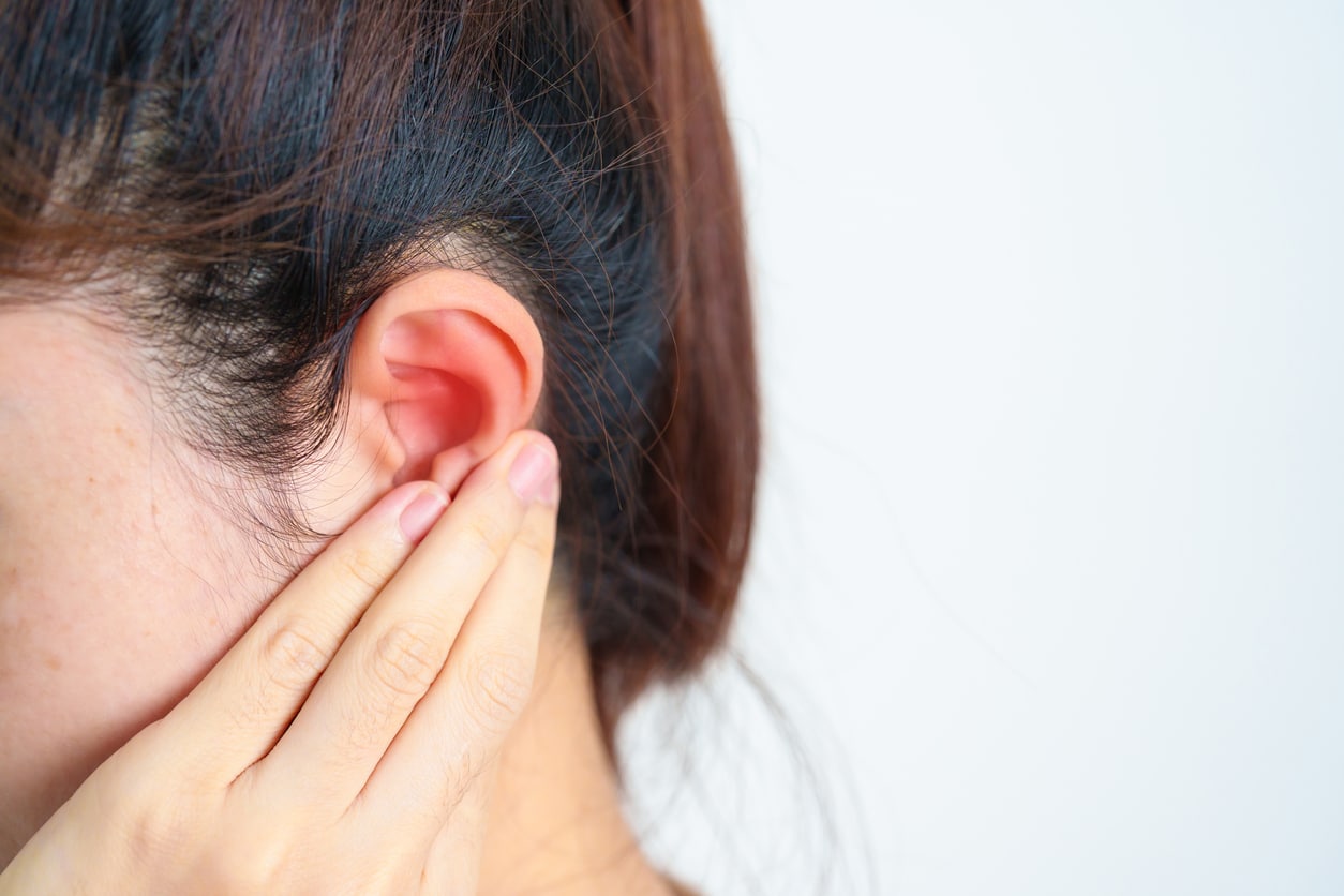 Woman holds hand behind ear