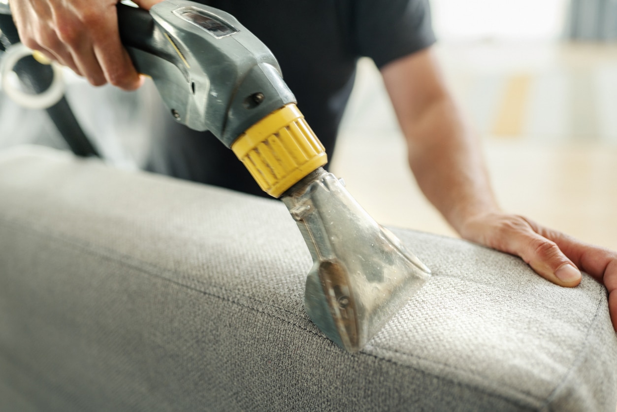 Man vacuuming his furniture during spring cleaning.