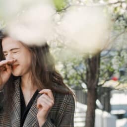 Woman scratching nose by trees