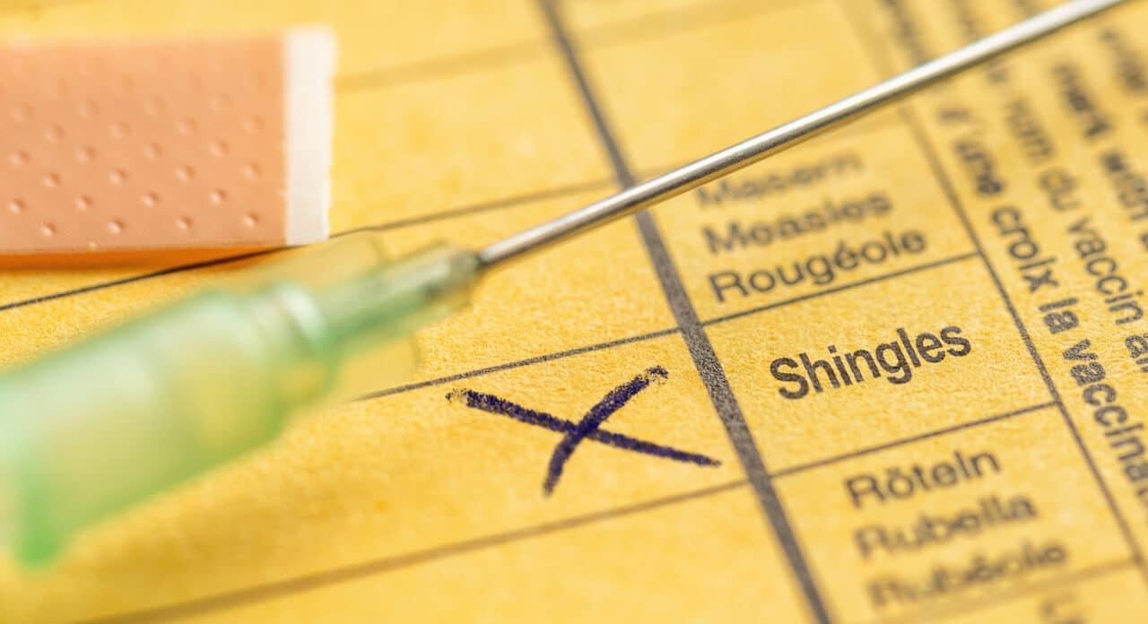 Close up of a shingles vaccine card and needle.