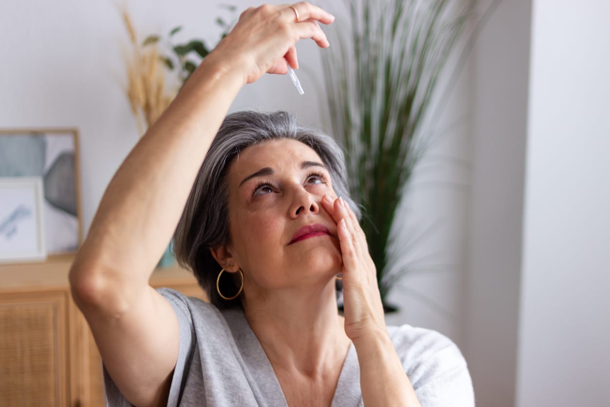 Senior woman applying eye drops suffering from allergies.
