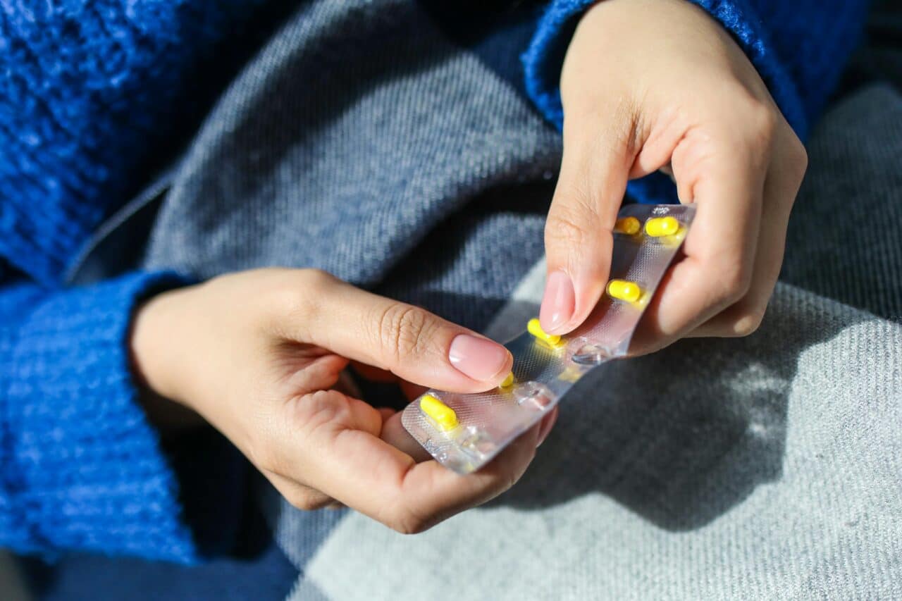 Person with allergies pops an antihistamine pill out of the packet.