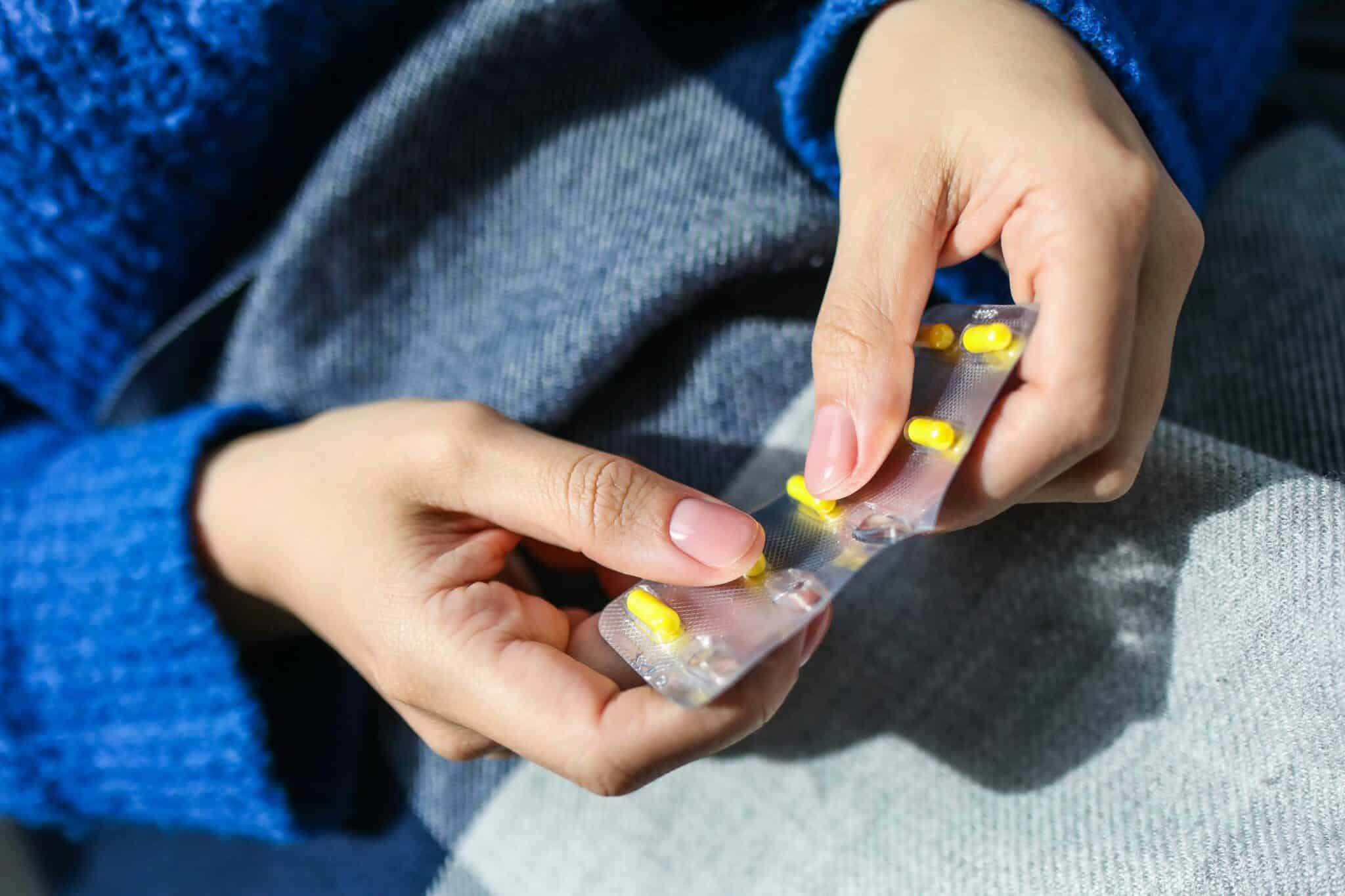 Person with allergies pops an antihistamine pill out of the packet.