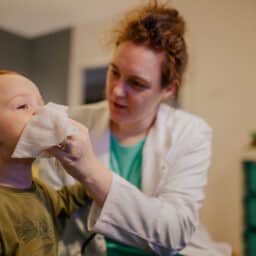 Allergist helps a child blow their nose after performing an allergy test.