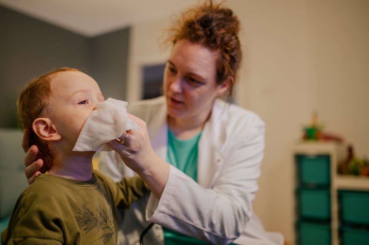 Allergist helps a child blow their nose after performing an allergy test.