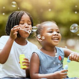 Two happy little girls blowing bubbles outside on a lovely spring day