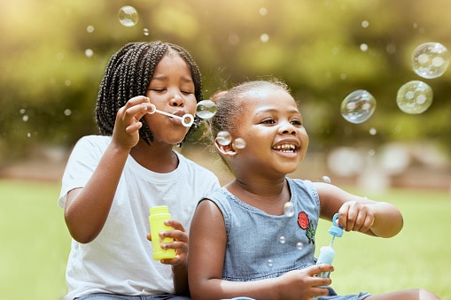 Two happy little girls blowing bubbles outside on a lovely spring day