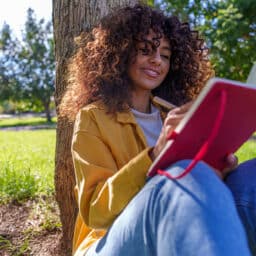 Happy woman writing in a symptom journal on a lovely spring day.