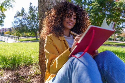 Happy woman writing in a symptom journal on a lovely spring day.
